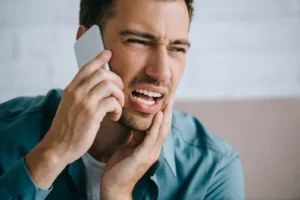 رجل يعاني من ألم زراعة الأسنان ويتحدث مع طبيبه